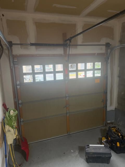 New garage door with window lites being installed, viewed from inside