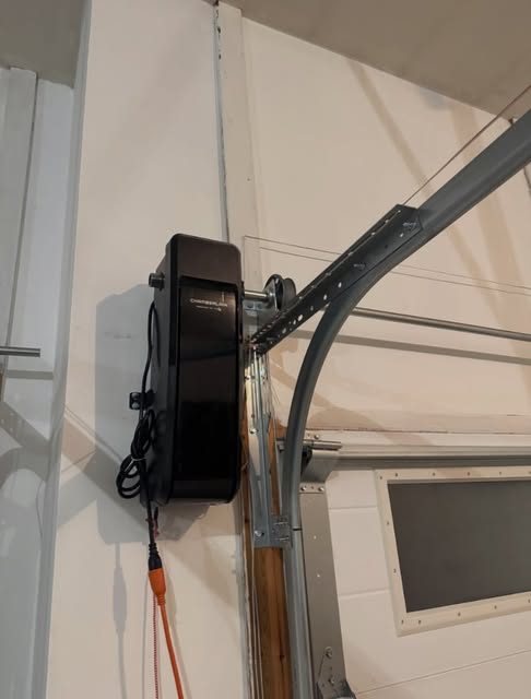 Wall-mount garage door opener installed beside the door track