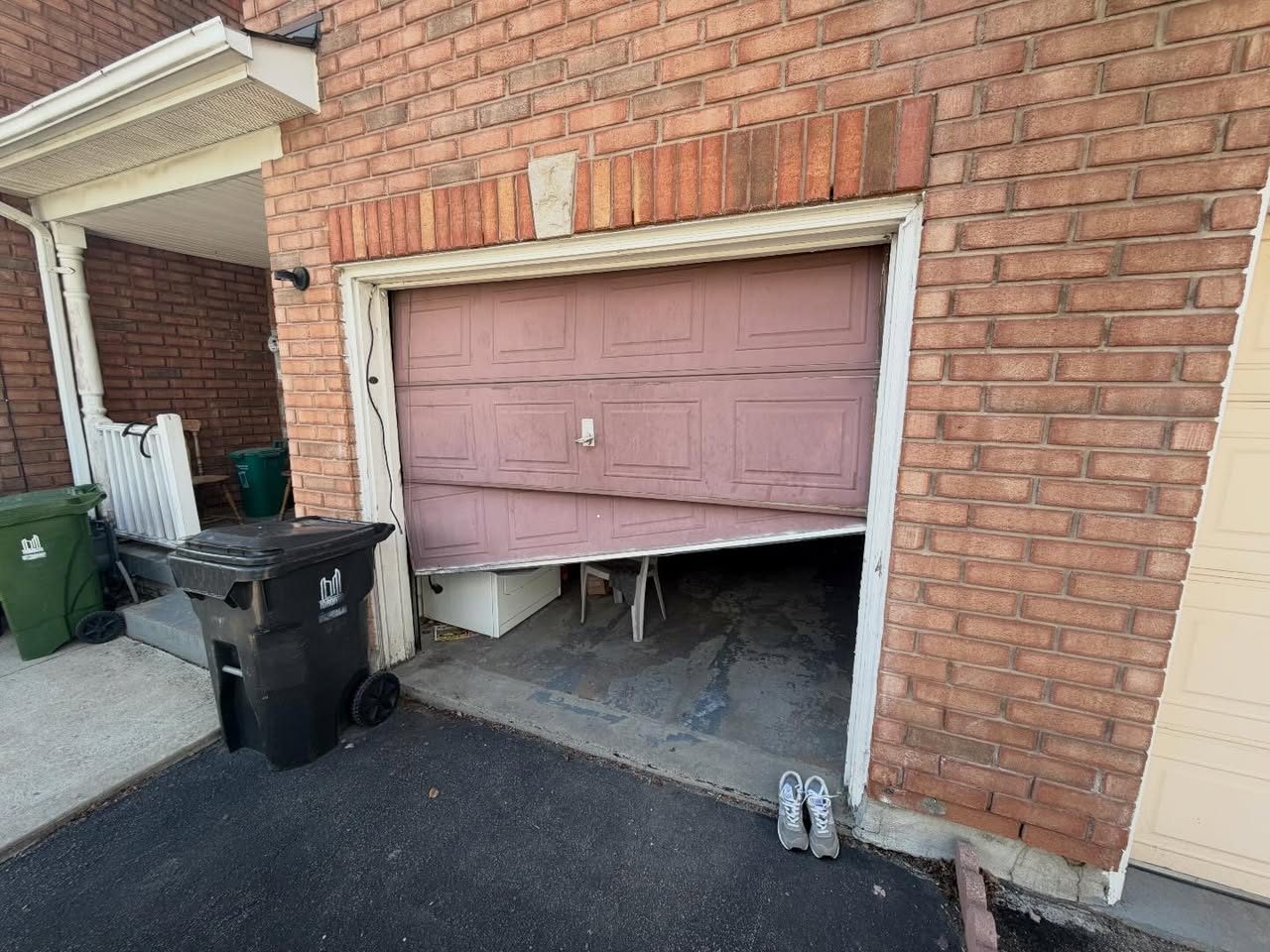 Garage door with a broken cable and bent bottom panel before repair