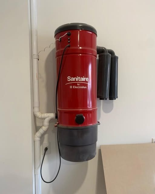 Red Sanitaire central vacuum power unit mounted on a wall